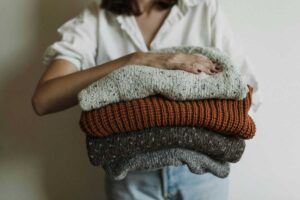 Donna che tiene pila di maglioni in mano