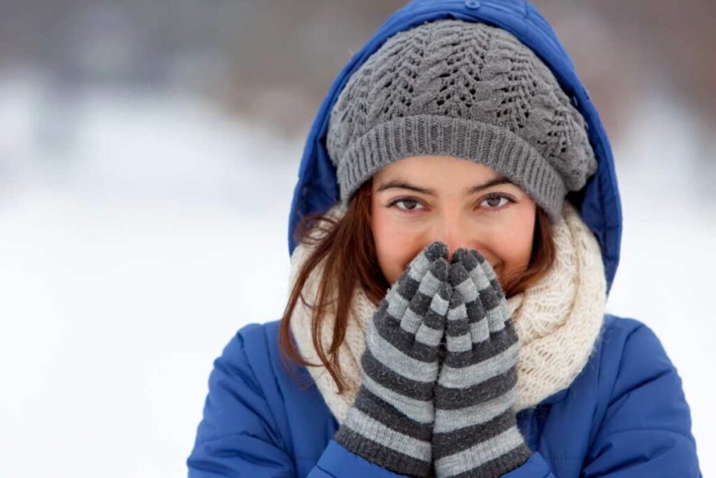 Donna infreddolita con guanti, sciarpa e cappello