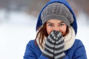Donna infreddolita con guanti, sciarpa e cappello