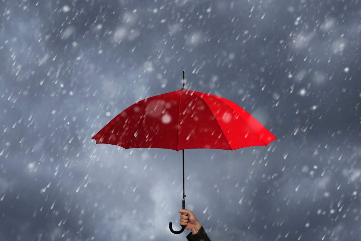 Ombrello rosso tenuto in mano sotto la pioggia