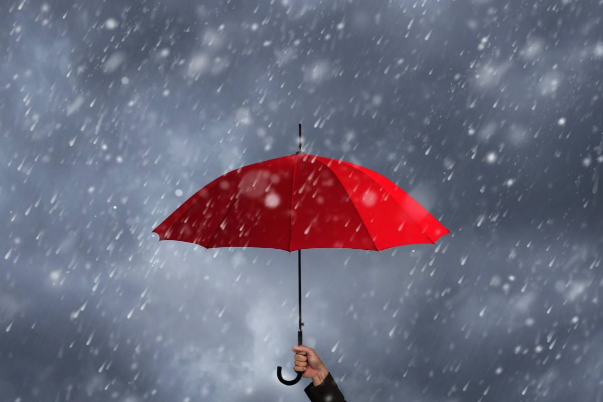 Ombrello rosso sotto la pioggia tenuto da una mano