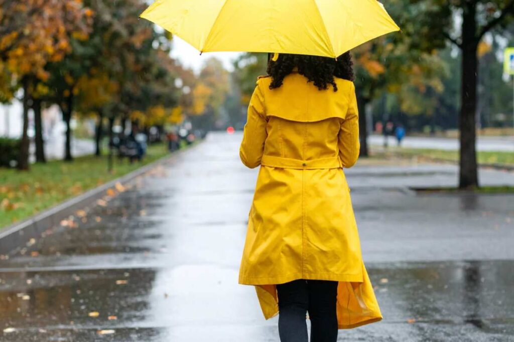 Donna che cammina sotto la pioggia con ombrello