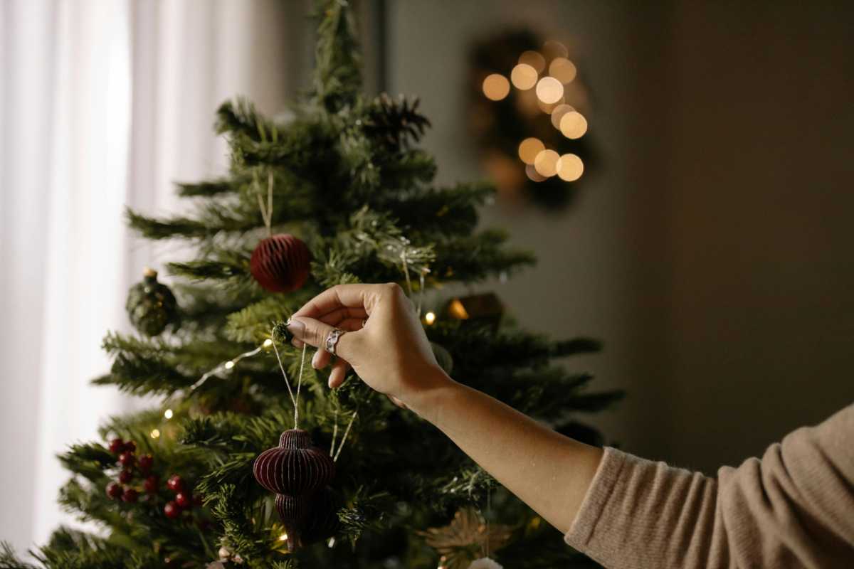 Persona che aggiunge addobbo all'albero di Natale