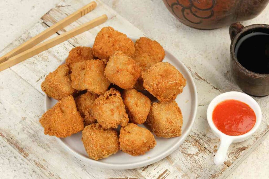 Cubetti di tofu fritto in un piatto con salsa accanto